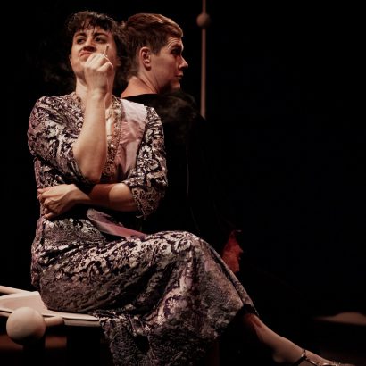 Evalyn Parry and Anna Chatterton together onstage in the play Gertrude and Alice. Both sitting and talking with their backs against each other.