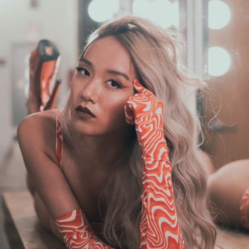 Headshot of Julie Phan laying on a counter in her change room wearing patterned gloves