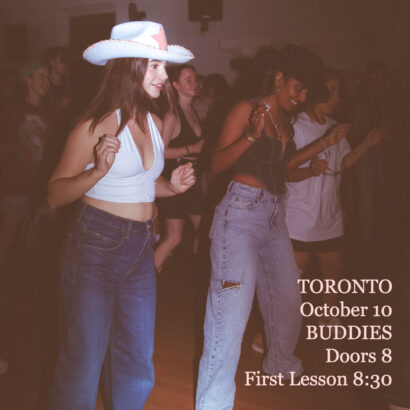 A photo of two hot queers in cowboy outfits dancing in an old meeting hall