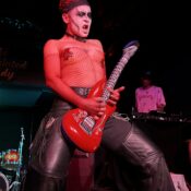 Image of El Experimento, playing guitar on stage in drag makeup.