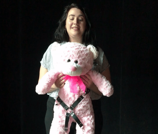 Desirée Leverenz leaning over and biting a pink bear in her hand